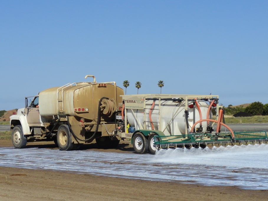 Water truck applying treatment to an unpaved road with a TerraTech spray rig